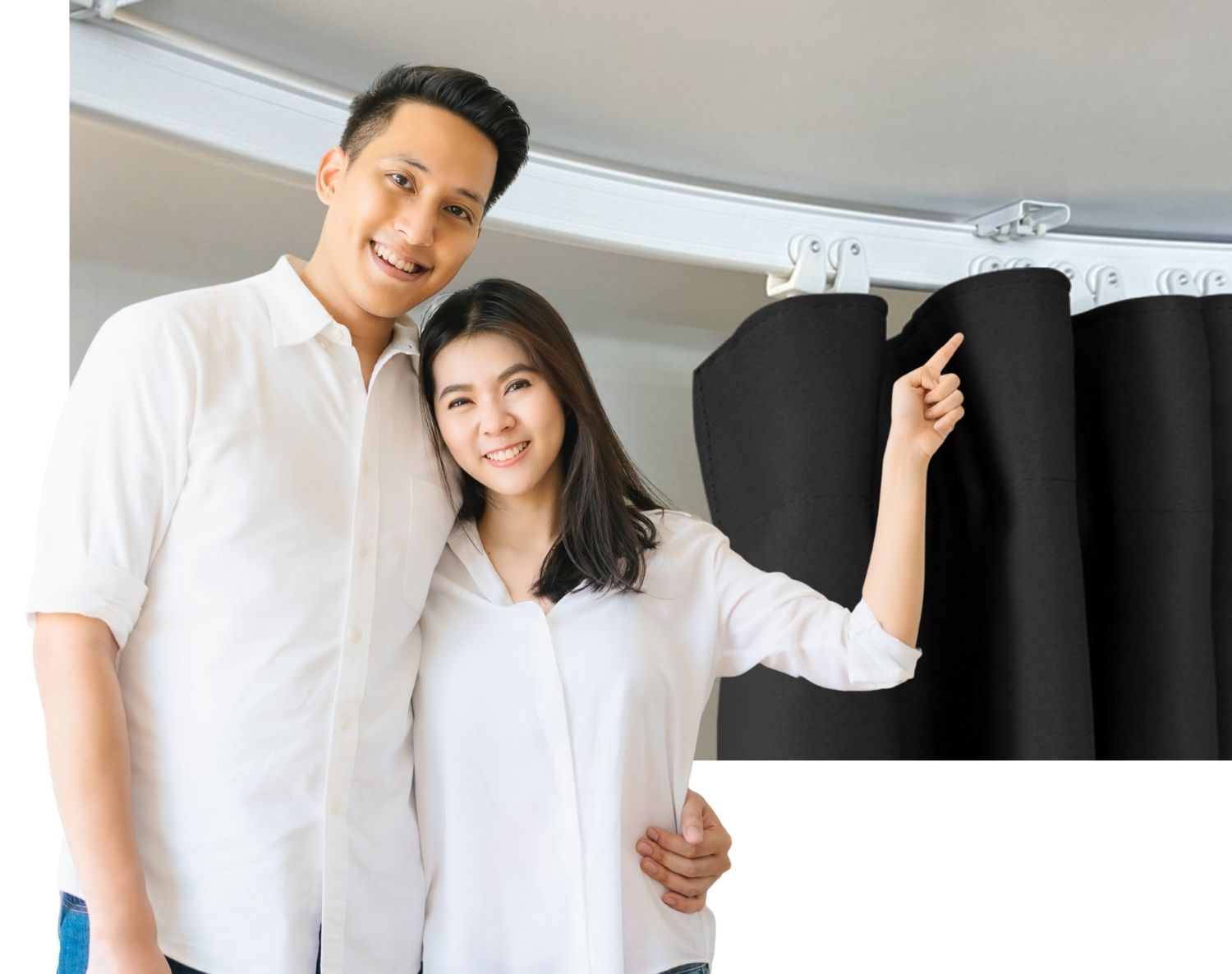 A couple standing beside curtains hung from a ceiling mounted curtain track that curves around the room